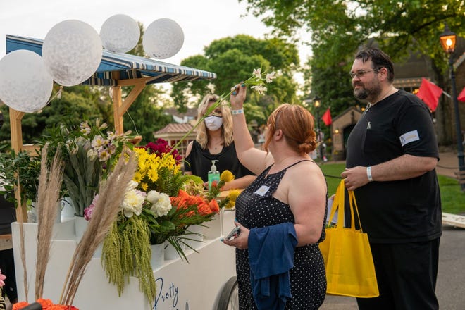 Jennifer Uetz and Matt Hartley check out flower samples at the Pretty Pedals Flower Cart, one of the Peddler's Village Outdoor Wedding Show exhibits on Friday in Buckingham.