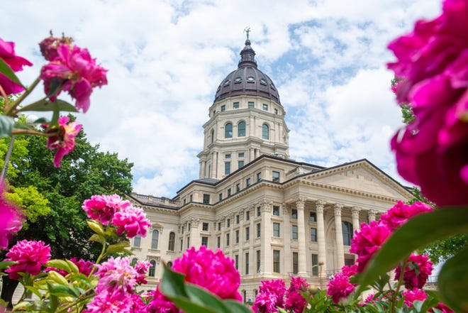 The Kansas Statehouse shines bright through a bed of peonies flowers Tuesday afternoon.