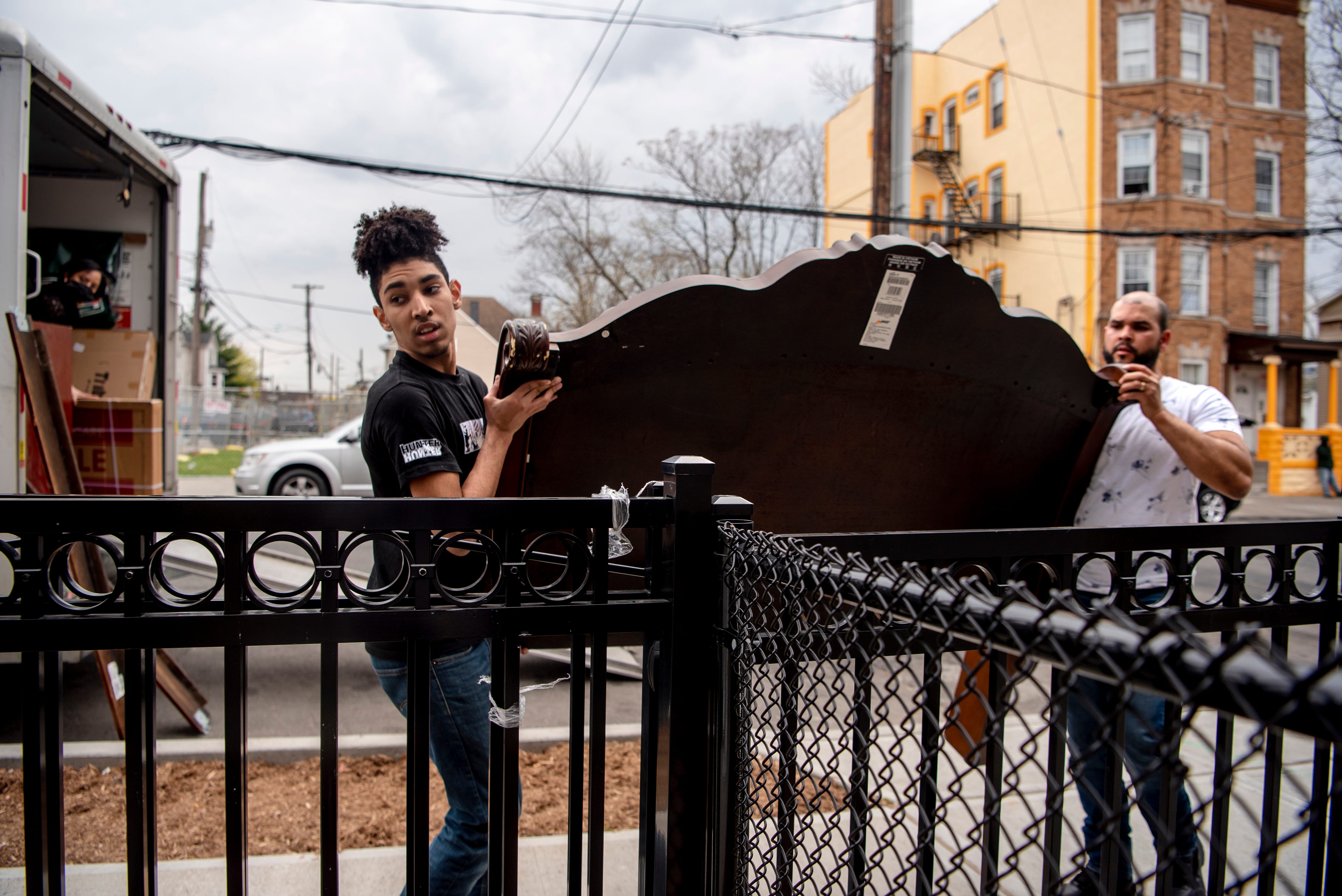 Carlos De Los Santos, 17 and his stepfather Ronny Brito unpack the moving van outside of the family's new Habitat for Humanity home on Hamilton Ave. in Paterson on April 9, 2021.