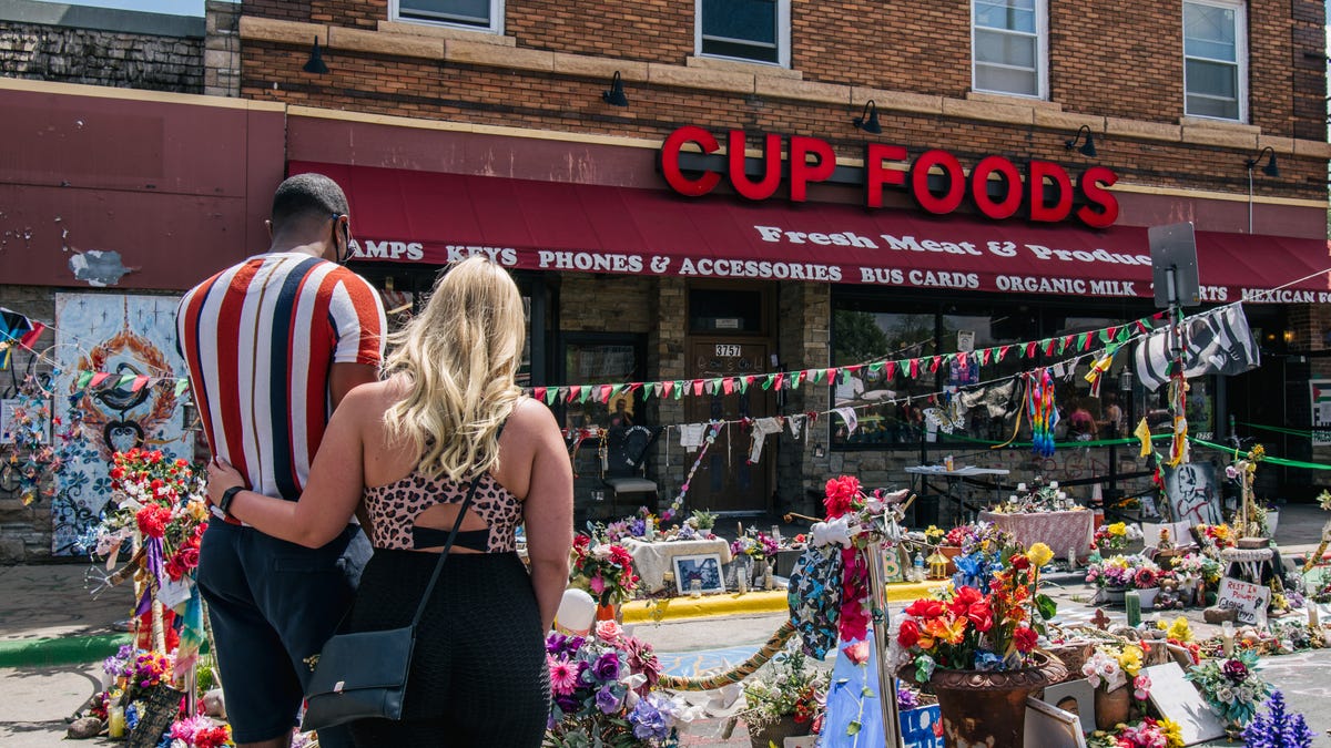 A couple pays their respects to George Floyd in the intersection of 38th Street and Chicago Avenue on May 25, 2021 in Minneapolis, Minnesota. In cities around the US groups honored the life of George Floyd, who was murdered by Minneapolis Police officer Derek Chauvin on May 25, 2020. 