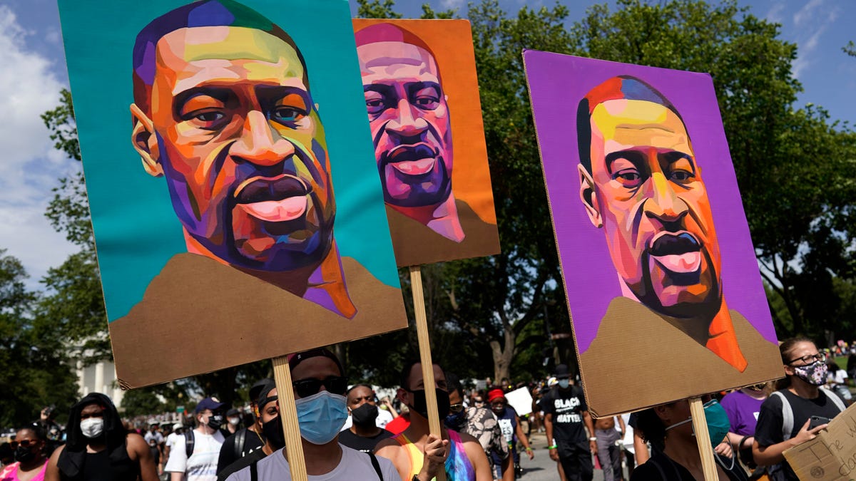 In this Aug. 28, 2020, file photo, people carry posters with George Floyd on them as they march from the Lincoln Memorial to the Martin Luther King Jr. Memorial in Washington.