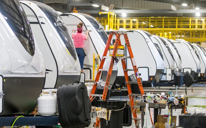 A worker installs graphics on an RV inside an East to West RV factory in Elkhart. RV production is booming throughout the Elkhart region, but it still isn't enough to catch up with demand.