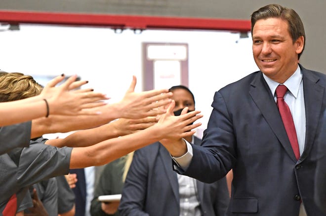 Gov. Ron DeSantis high-fives students as he enters the Sarasota School of Arts & Sciences gymnasium for an Wednesday afternoon press conference in Sarasota, Florida, on May 26, 2021.