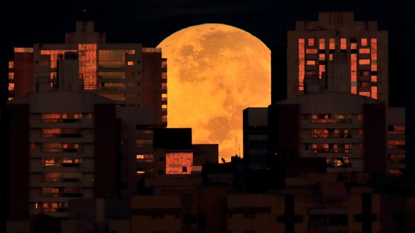 The moon is partially covered by buildings in Bras