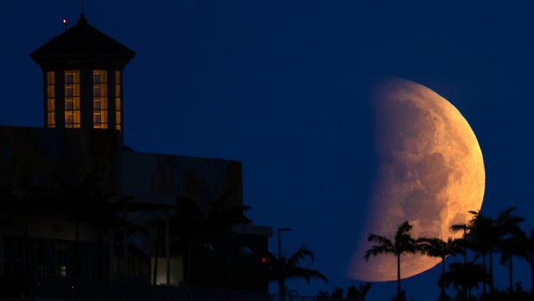 The partially eclipsed moon sets over West Palm Be