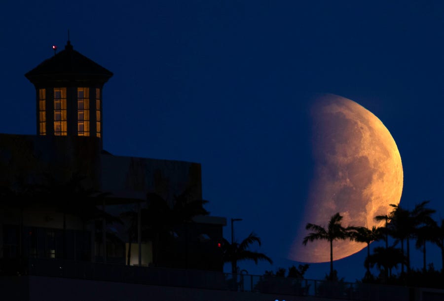 The partially eclipsed moon sets over West Palm Beach Wednesday morning, May 26, 2021. The moon was near its closest approach to Earth, making it a "supermoon," and meaning it appears slightly larger in the sky.