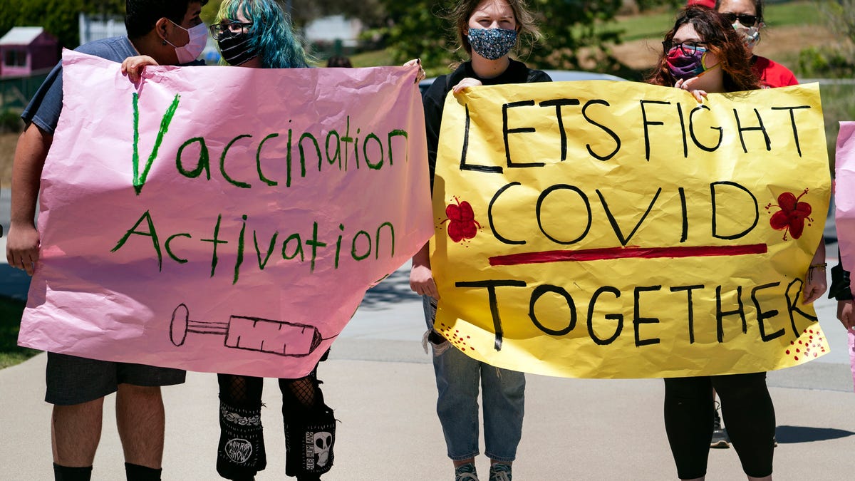 San Pedro High School students hold vaccination signs at a school-based COVID-19 vaccination event for students 12 and older in San Pedro, Calif., Monday, May 24, 2021. Schools are turning to mascots, prizes and contests to entice youth ages 12 and up to get vaccinated against the coronavirus before summer break.