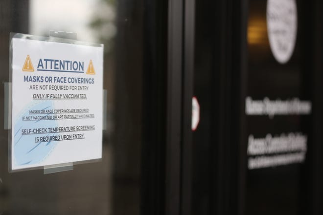 A sign instructs visitors to the Kansas Department of Revenue on mask wearing. State employees will return to working remotely amid a rising surge of COVID-19 cases, Gov. Laura Kelly's administration announced Wednesday.