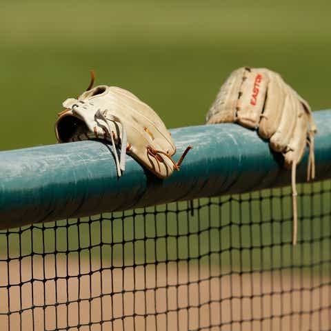 Gloves sit on top of a softball fence