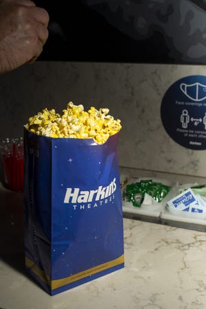 A moviegoer sprinkles salt over his popcorn at Harkins Theatre Camelview at Scottsdale Fashion Square in Scottsdale, Ariz., on May 24, 2021.