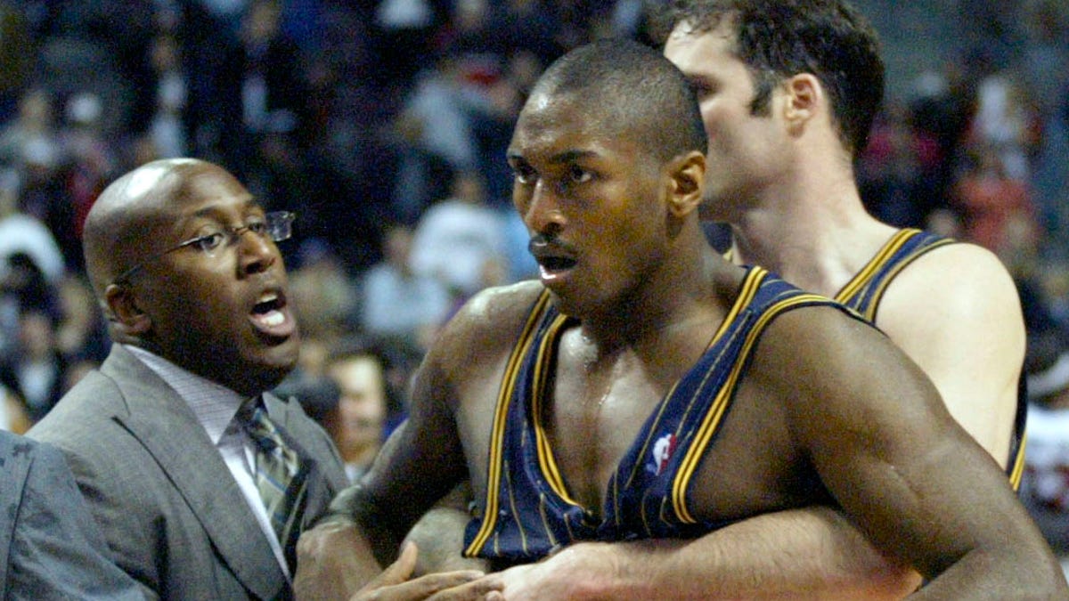 Ron Artest, now known as Metta Sandiford-Artest, is restrained by teammate Austin Croshere and Pacers' assistant coach Mike Brown during the "Malace at the Palace" in 2004.