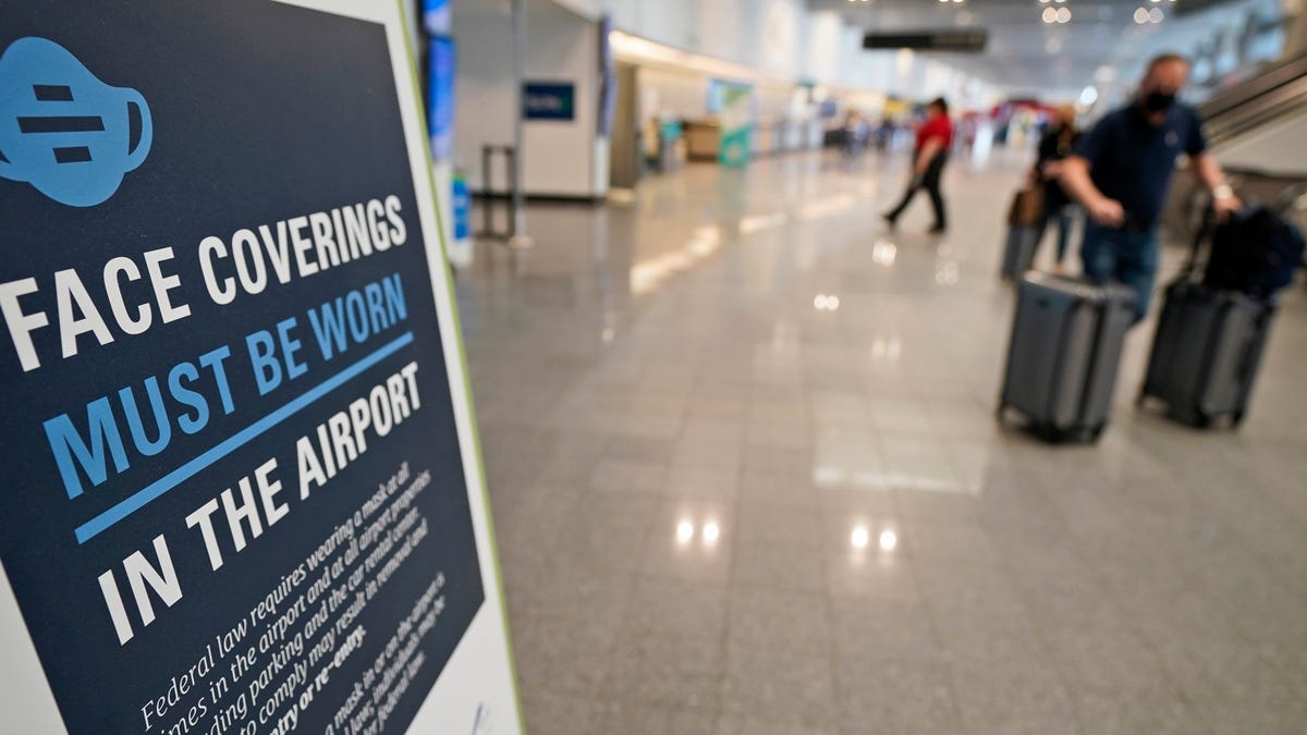 A sign requiring masks is displayed as travelers move about at Cleveland Hopkins International Airport on Wednesday.