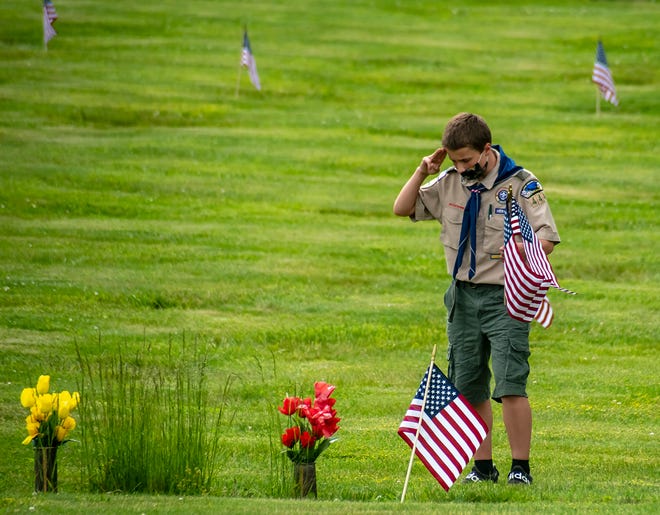 Joseph Castelli of New Sewickley Township, 14 and a member of Boy Scout Troop 444, salutes at the gravesite of a veteran after he placed an American flag at Sylvania Hills Memorial Cemetery Thursday, in preparation for Memorial Day.