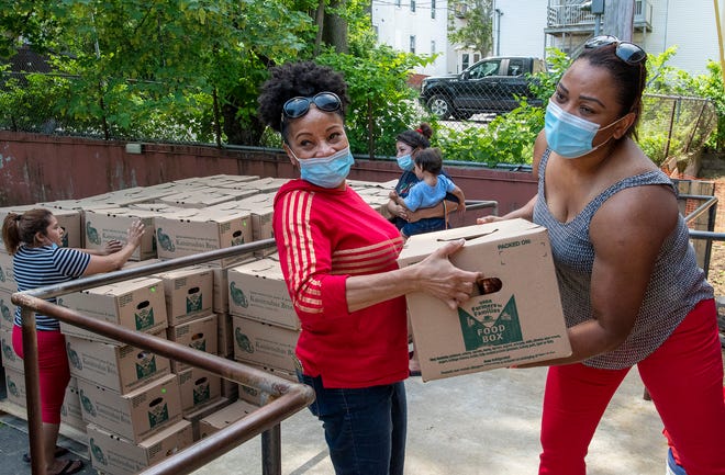 Lupita Made, center, and Dilannia Gomez unload boxes of donated food from a truck Wednesday, May 26, 2021.