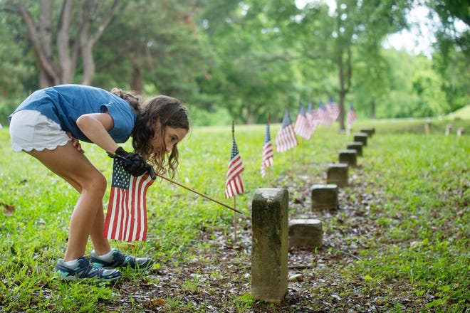 Avery Peacock, 10, checks the date on a headstone at the Vicksburg National Cemetery during the Memorial Day flag placement event in Vicksburg, Miss., Friday, May 28, 2021. 