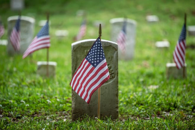 Flags are placed near headstones at the Vicksburg National Cemetery during the Memorial Day flag placement event in Vicksburg, Miss., Friday, May 28, 2021. Nearly 1,700 flags were placed.