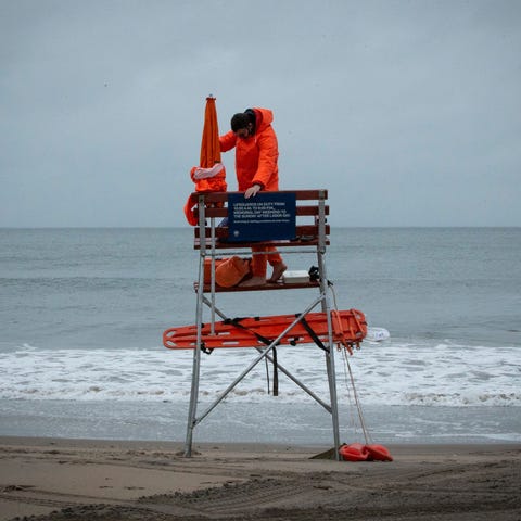 A lifeguard sets up his equipment as rain falls du