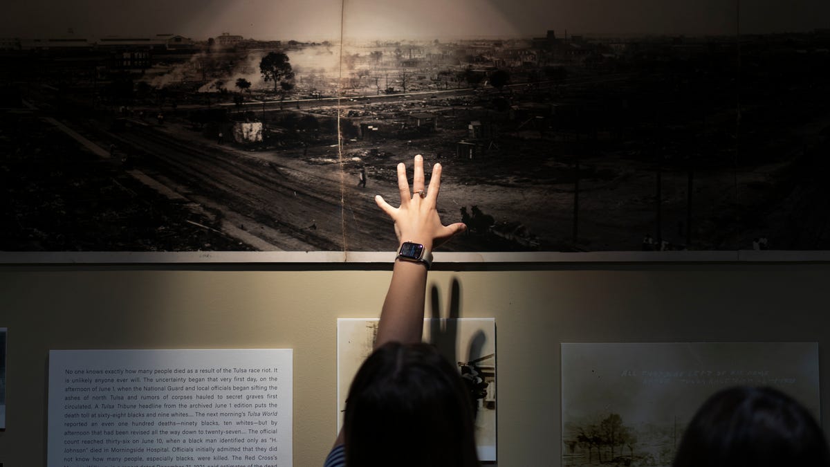 A woman points at a picture of devastation from the Tulsa Race Massacre in a prayer room dedicated to the massacre at the First Baptist Tulsa church during centennial commemorations, Sunday, May 30, 2021, in Tulsa, Ok. 