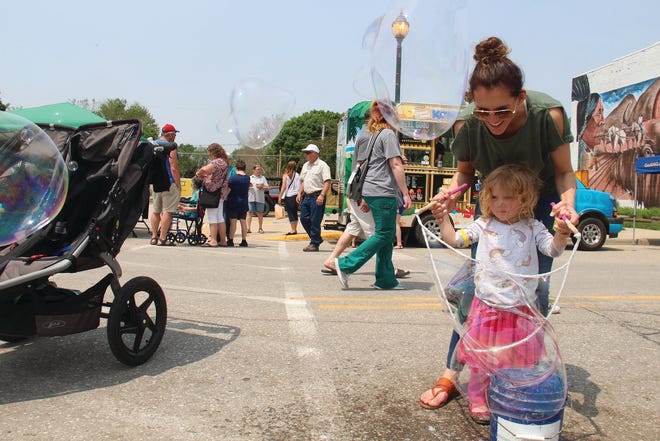 Danie Gohr helps her daughter, Charlie, try her hand with the bubbles at a vendor's booth during Woodward Friends and Neighbors Day in 2019.