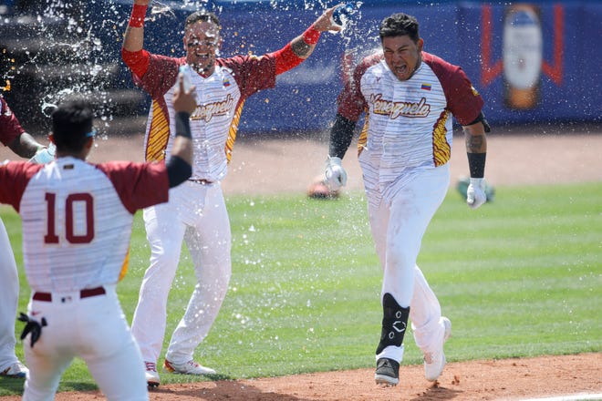 Venezuela right fielder Diego Rincones (30) celebrates with teammates at home plate after connecting for a walk-off home run in the 10th inning to beat Colombia Tuesday in Port St. Lucie.