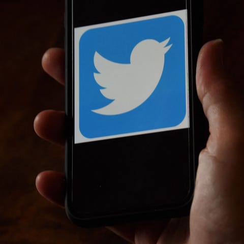 a Twitter logo is displayed on a mobile phone.