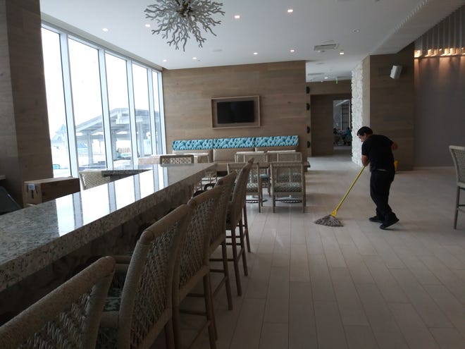 A worker cleans the floor on Friday near the hotel bar in the lobby of the newly opened Daytona Grande, the hotel portion of the $192 million Protogroup twin-tower condominium project. The hotel was expected to welcome its first guests on Friday, employees said.