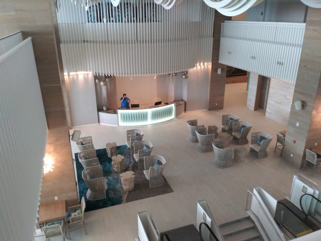 A desk clerk works on Friday in the lobby of the newly opened Daytona Grande, the hotel portion of the $192 million Protogroup twin-tower hotel-condominium project. Some hotel amenities, including its pool and fitness center, aren't yet open.
