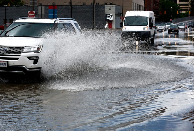 A car drives through a large puddle on N. 3rd St. after crossing E Spring St. Downtown on Monday, June 7, 2021, after a heavy rain.