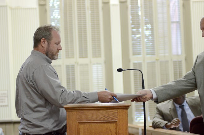 Ascension Parish President Clint Cointment receives a lawsuit from District 4’s Corey Orgeron during the July 3 Ascension Parish Council meeting at the courthouse in Donaldsonville.