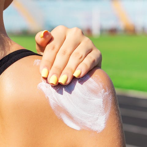 Fitness woman is applying sunscreen on her shoulde