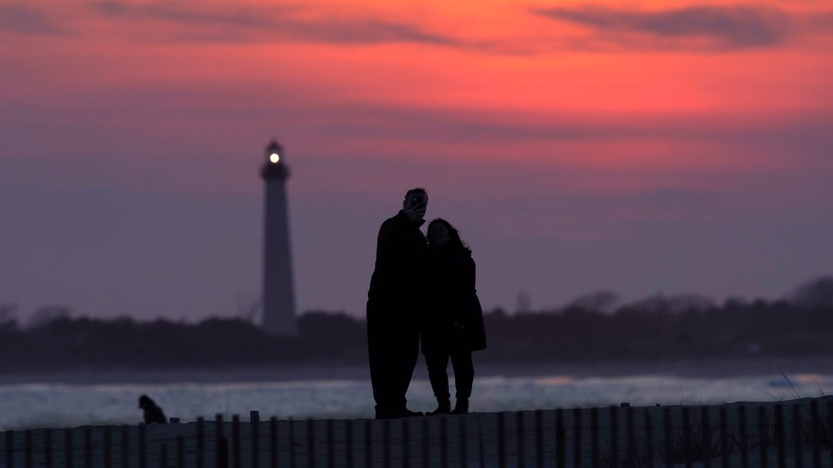 Visitors to Cape May, New Jersey, watch the sunset behind the Cape May Lighthouse on April 8, 2021. With the ocean on one side and grand Victorian homes on the other, Cape May offers an alternative vacation location with expansive views.