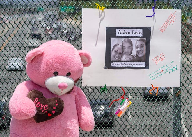 A large stuffed toy and poster board decorated with a photo and notes are part of a memorial on a flyover in Orange, California, to Aiden Lewis, 6, who was shot and killed during a roadside attack.