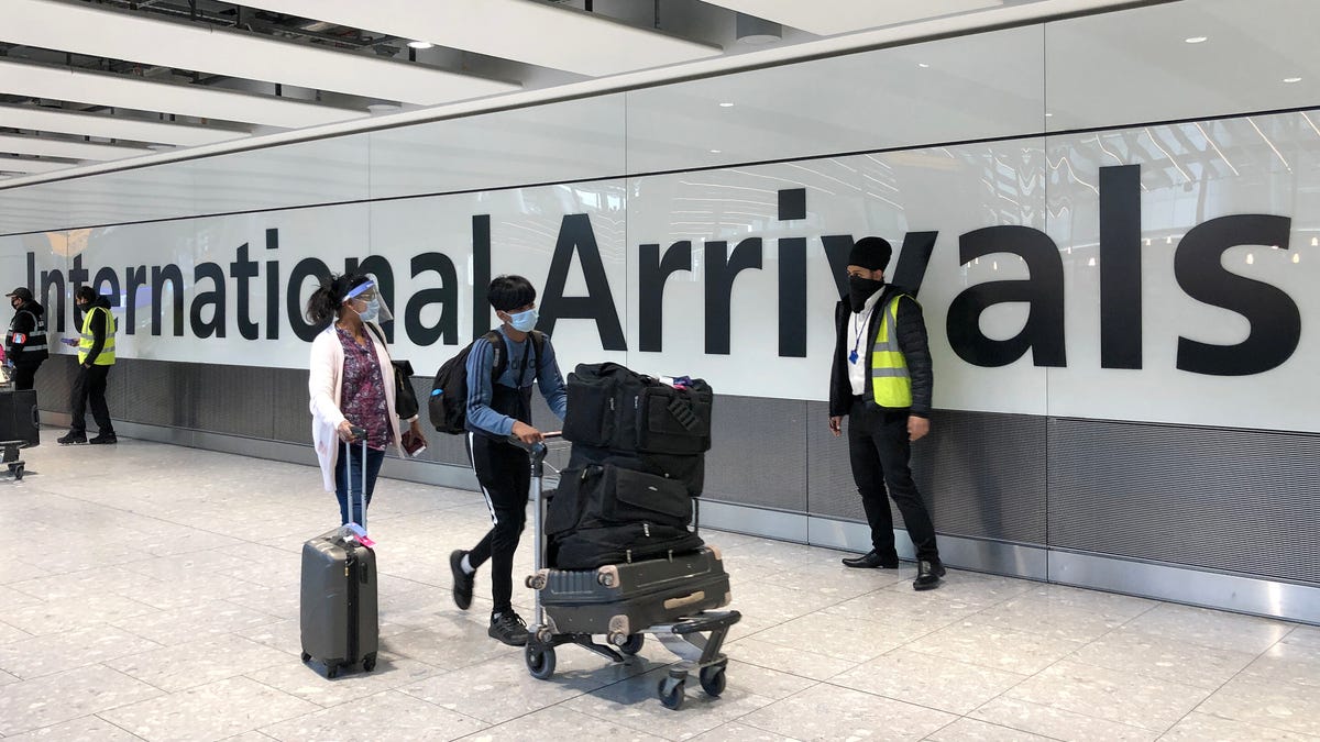 Passengers are escorted through the arrivals area of terminal 5 towards coaches destined for quarantine hotels, after landing at Heathrow Airport on April 23, 2021, in London.