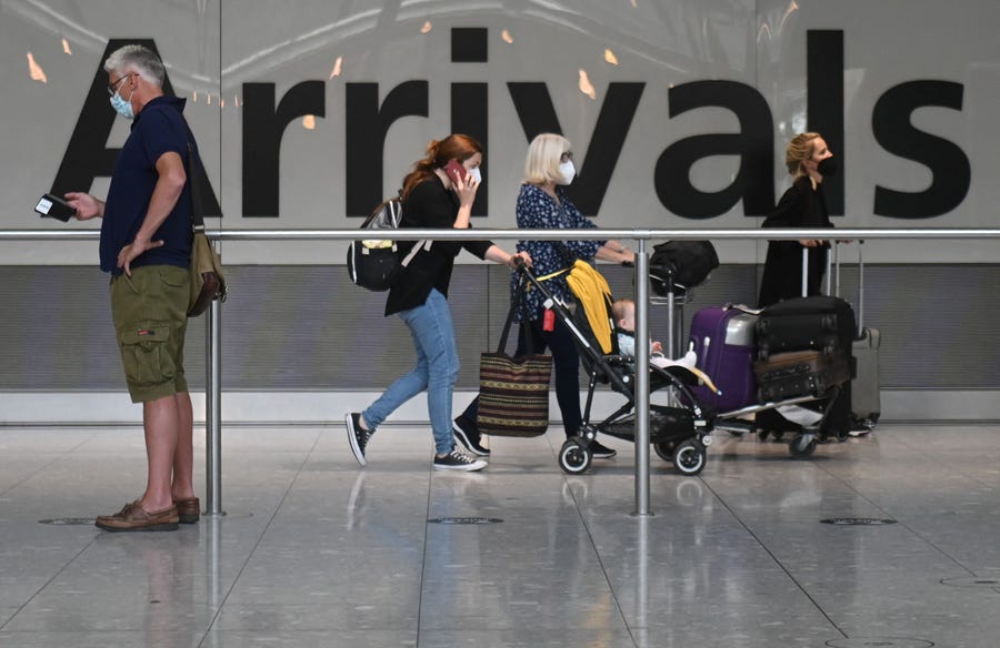Passengers push their luggage on arrival in Terminal 5 at Heathrow Airport in London, on June 3, 2021.