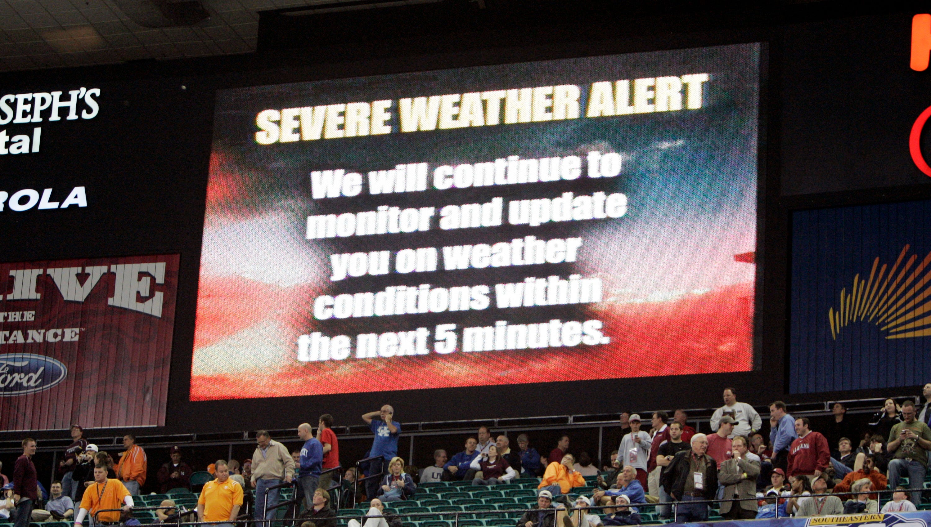 A weather warning is displayed on a television screen hanging near the basketball court.