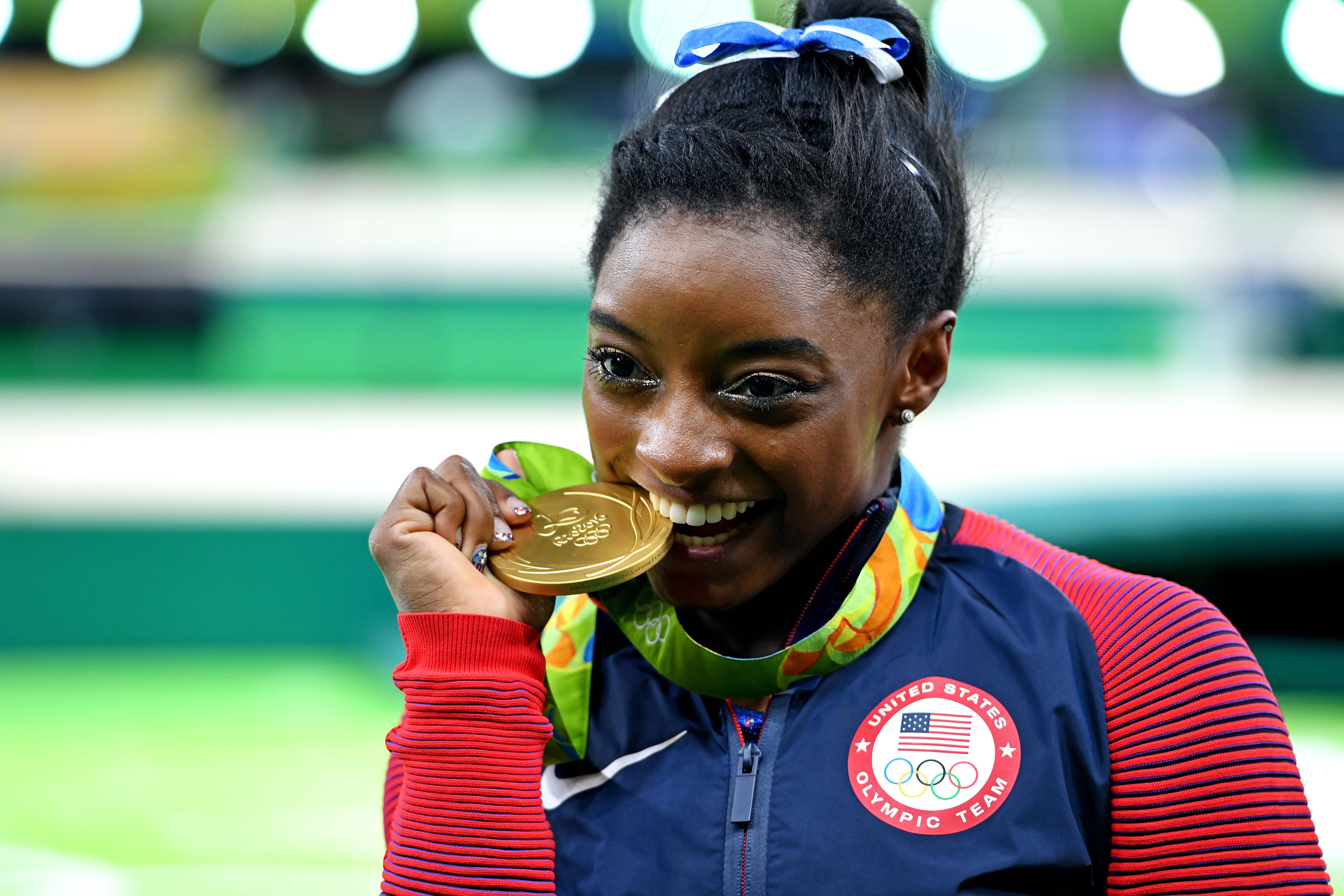 Simone Biles bites an Olympic gold medal in celebration.