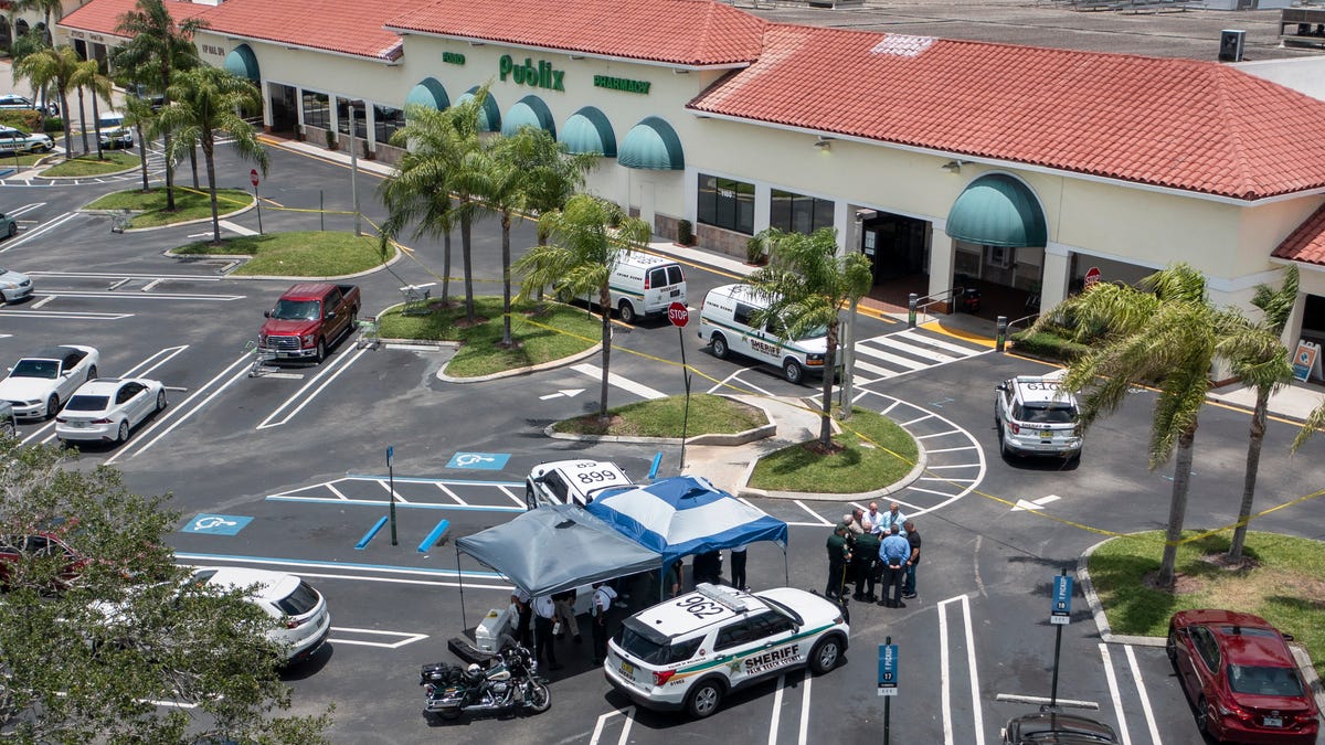 Police gather at a Publix shopping center where police say three people were shot and killed in Royal Palm Beach, Fla., on June 10.