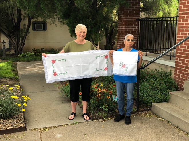 Phyllis Doucette (left) poses with Kina Gonzalez with the tablecloths Gonzalez cross-stitched.