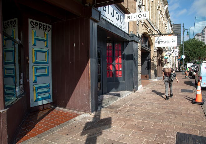 People walk down Sixth Street in Austin on Saturday morning, hours after 14 people were injured in a shooting in the popular entertainment district.  Business owners are concerned about the potential impact the incident could have on Sixth Street's reputation and Austin's tourism industry.