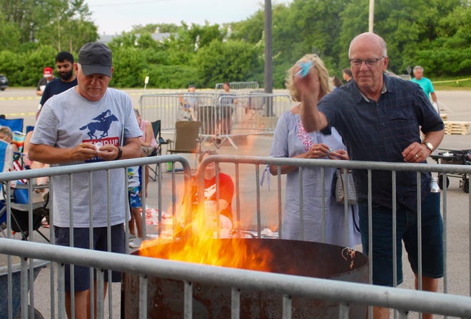 Attendees throw facemasks into a fire during the Stand Up Michigan Mask Burning event on Friday, June 11, 2021, outside the DeltaPlex Arena near Grand Rapids, Mich.