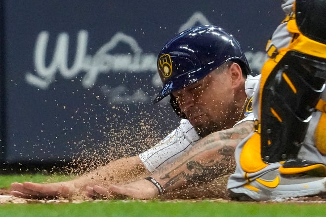 The Brewers' Jace Peterson slides safely past Pirates catcher Michael Perez as he score on a squeeze bunt by Brandon Woodruff during the second inning.