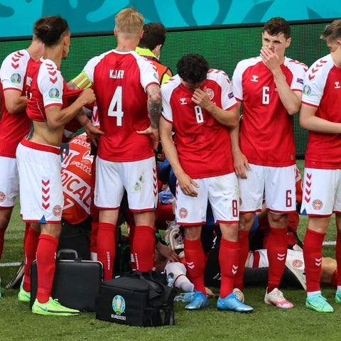 Denmark's players gather as paramedics attend to m