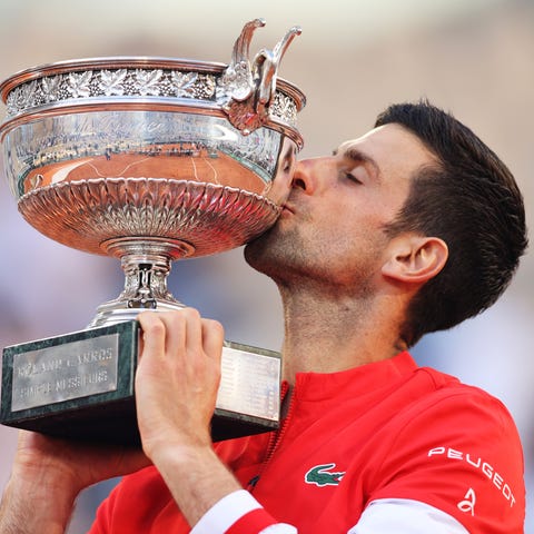 Novak Djokovic celebrates as he kisses the trophy 