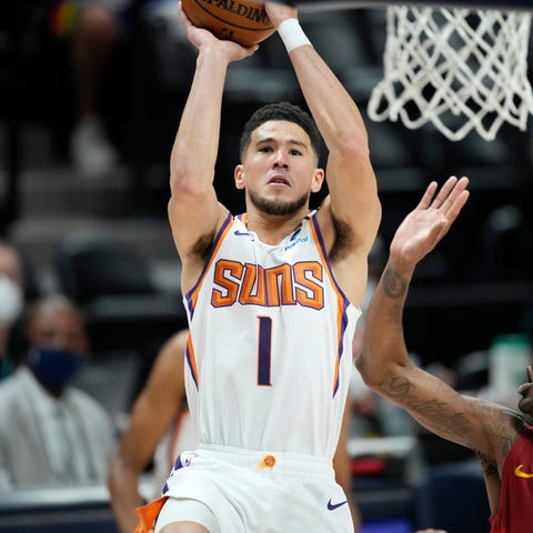 Phoenix Suns guard Devin Booker, left, goes up for
