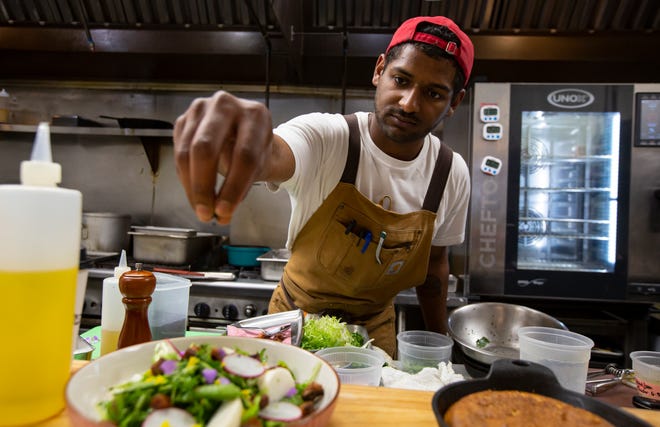Matt Larkin, junior sous chef of Chapman's Eat Market, sprinkles the finishing touches on a salad that will be on a special Juneteenth menu Saturday. Larkin was inspired to create the menu based on food by renowned Black chef and cookbook author Edna Lewis.