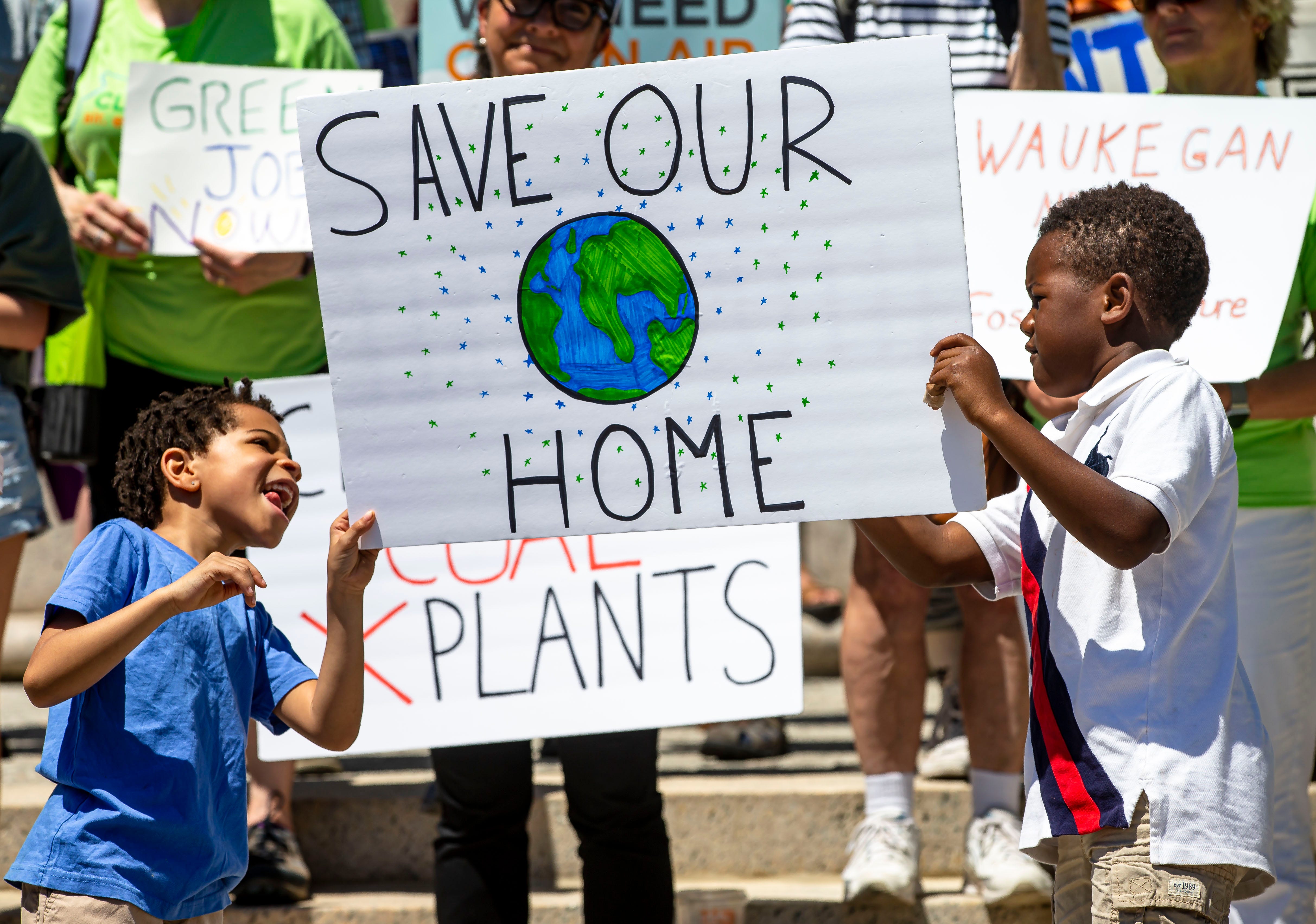 Kaiden Trotter, 6, left, and Tise Ogunrinde, 7, join together to hold up a sign for the “Rally for a Fossil Free Future” at the Illinois State Capitol in Springfield, Ill., Tuesday, June 15, 2021. Illinois lawmakers planned to return to the Capitol Tuesday and Wednesday to consider an energy overhaul bill. [Justin L. Fowler/The State Journal-Register]