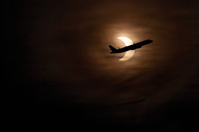 A plane leaving Logan Airport crosses through the partial solar eclipse on June 11.