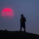 The sun glows red from smoke from the Telegraph Fire east of Phoenix as a hiker pauses on a trail at Papago Park on June 14, 2021. The National Weather Service Phoenix issued an excessive heat warning for portions of south central Arizona through the week.