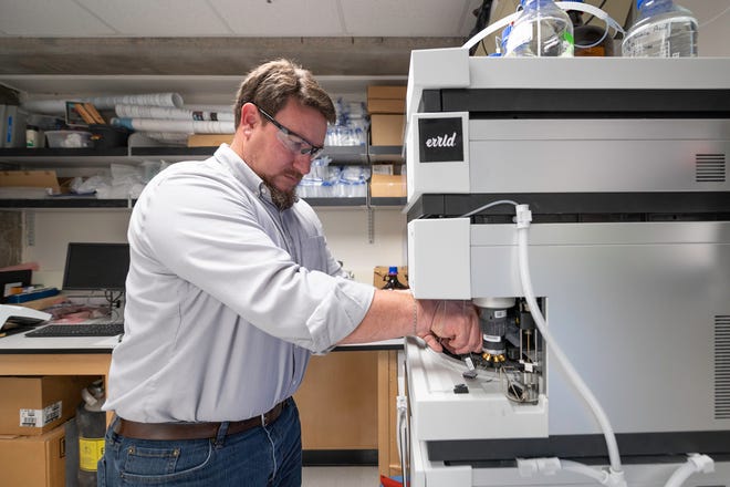 Chad Kinney, director of the Institute of Cannabis Research at Colorado State University Pueblo, loads a high-performance liquid chromatograph that will extract cannabinoids at the university on Wednesday June 16, 2021.