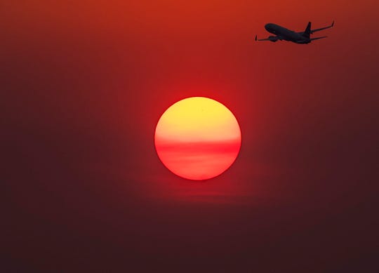 A plane flies near the sun as it glows red from smoke from the Telegraph Fire burning east of Phoenix June 15, 2021.The National Weather Service Phoenix AZ issued an excessive heat warning for portions of south central Arizona through the week.